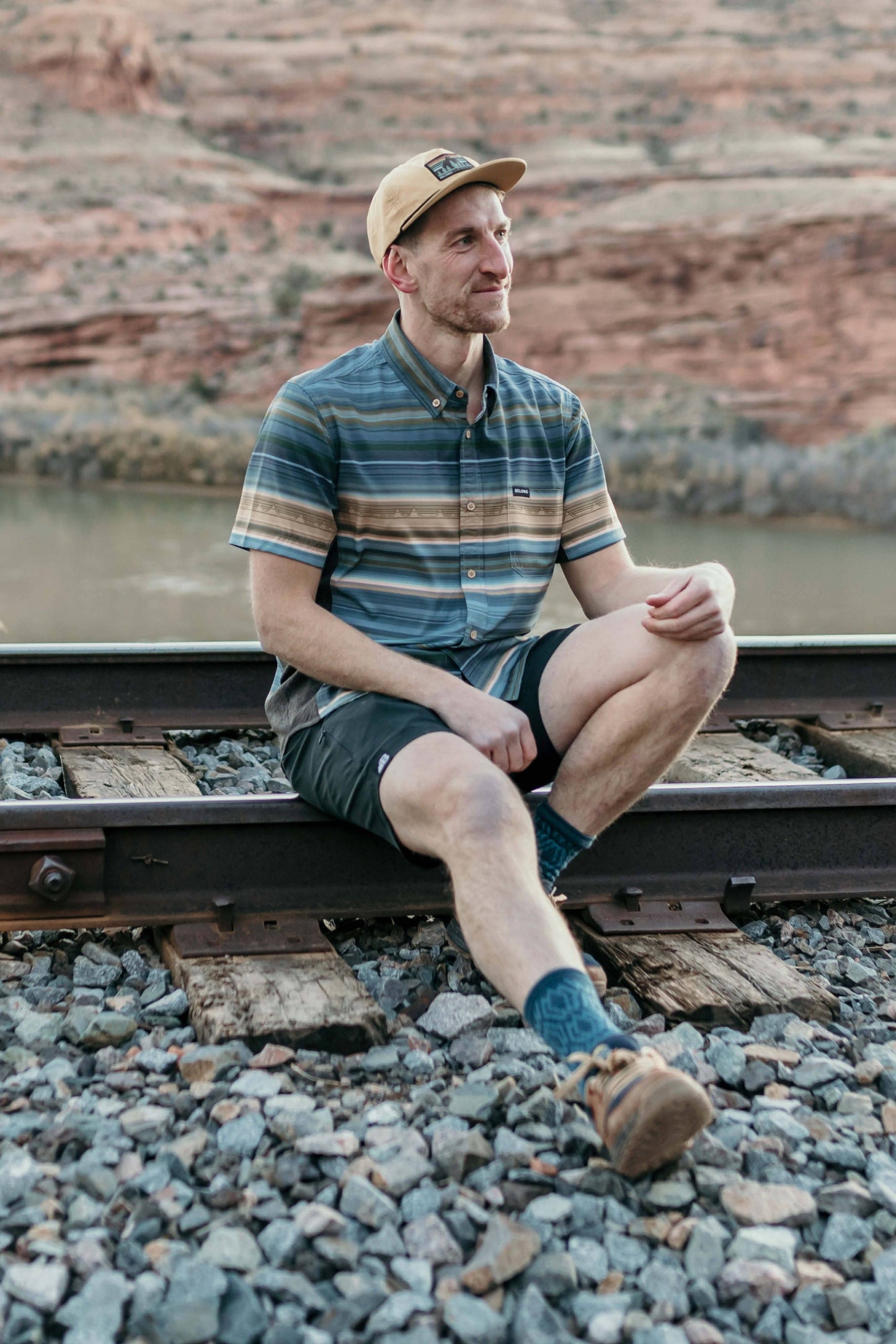 The Vista Stretch Button Down from Belong Designs features a modern, casual design in Summit Teal. This short-sleeve shirt includes a buttoned-down collar and is crafted from wrinkle-resistant fabric. It also comes with a small chest pocket adorned with a logo patch reading "Belong Designs.