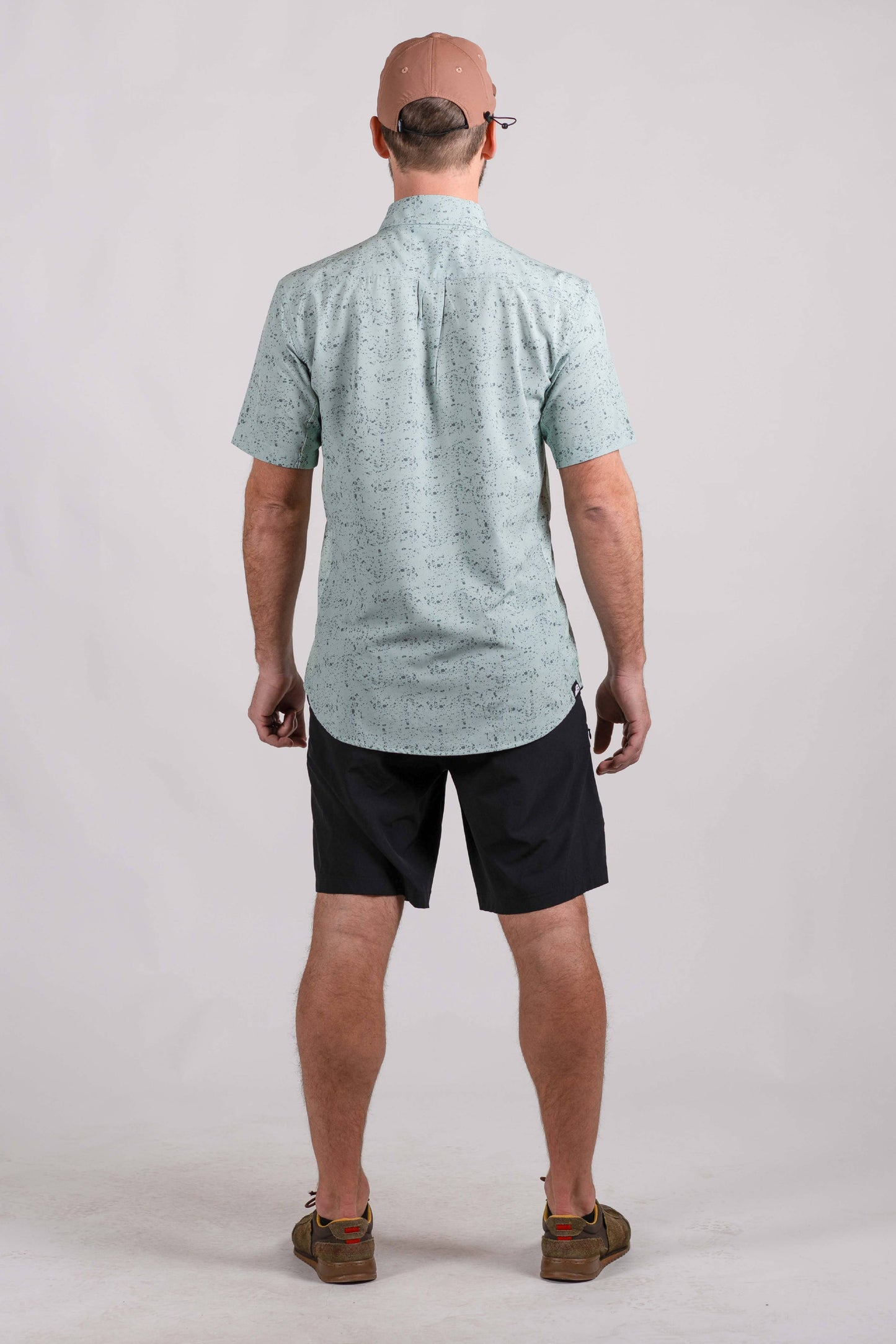 The Vista Stretch Button Down from Belong Designs features a modern, casual design in Summit Teal. This short-sleeve shirt includes a buttoned-down collar and is crafted from wrinkle-resistant fabric. It also comes with a small chest pocket adorned with a logo patch reading "Belong Designs.
