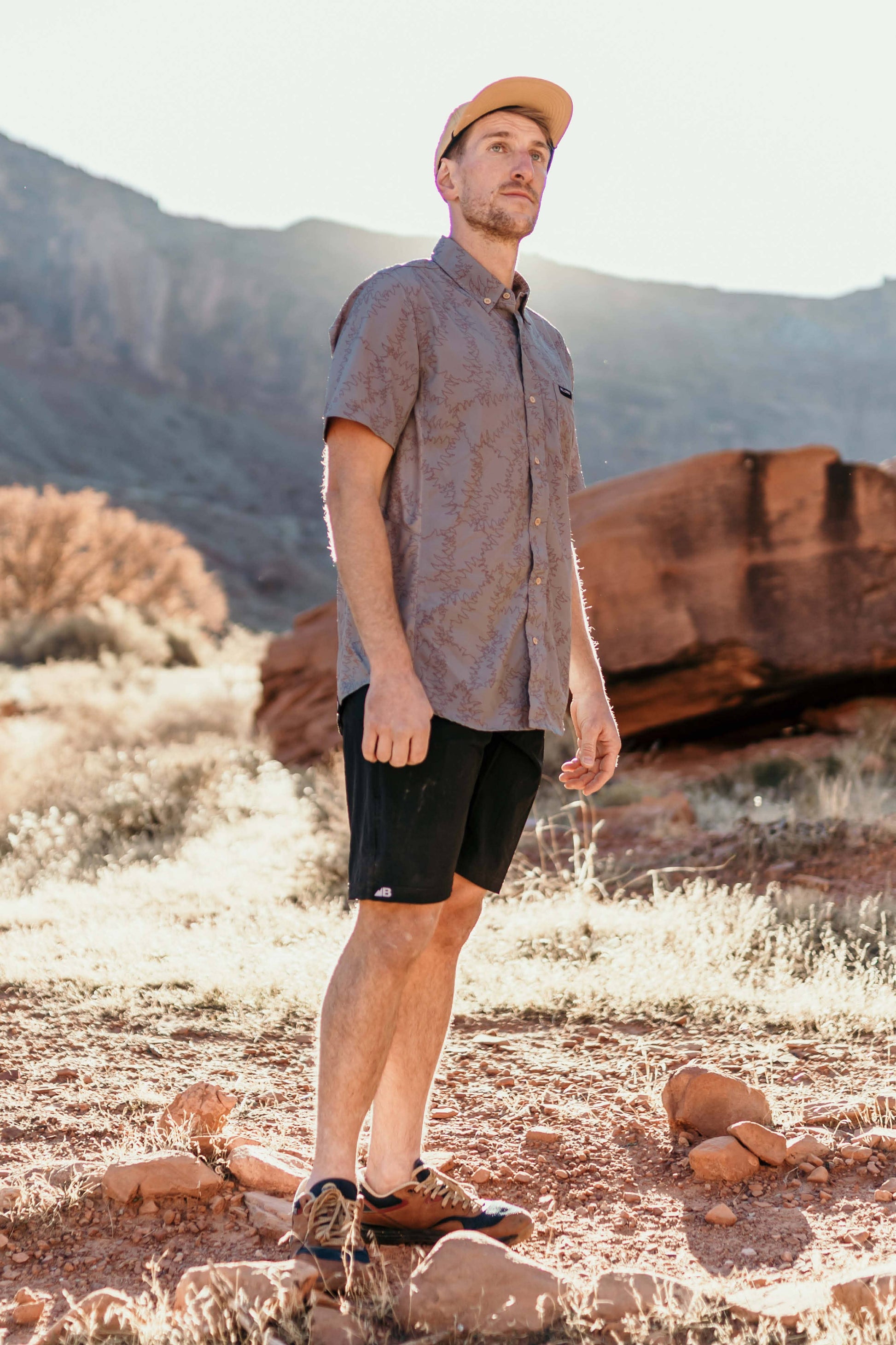 The Vista Stretch Button Down from Belong Designs features a modern, casual design in Summit Teal. This short-sleeve shirt includes a buttoned-down collar and is crafted from wrinkle-resistant fabric. It also comes with a small chest pocket adorned with a logo patch reading "Belong Designs.