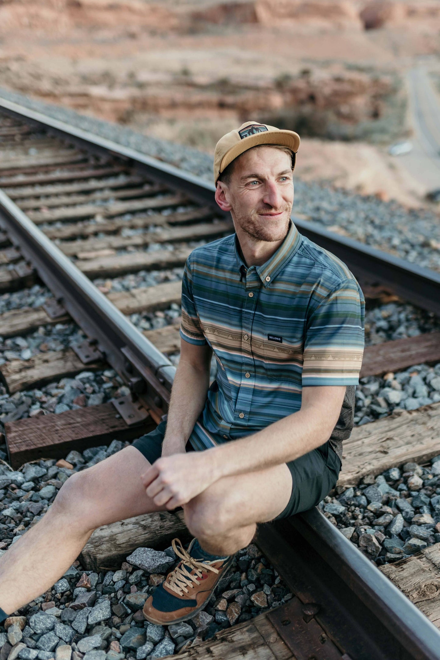 The Vista Stretch Button Down from Belong Designs features a modern, casual design in Summit Teal. This short-sleeve shirt includes a buttoned-down collar and is crafted from wrinkle-resistant fabric. It also comes with a small chest pocket adorned with a logo patch reading "Belong Designs.