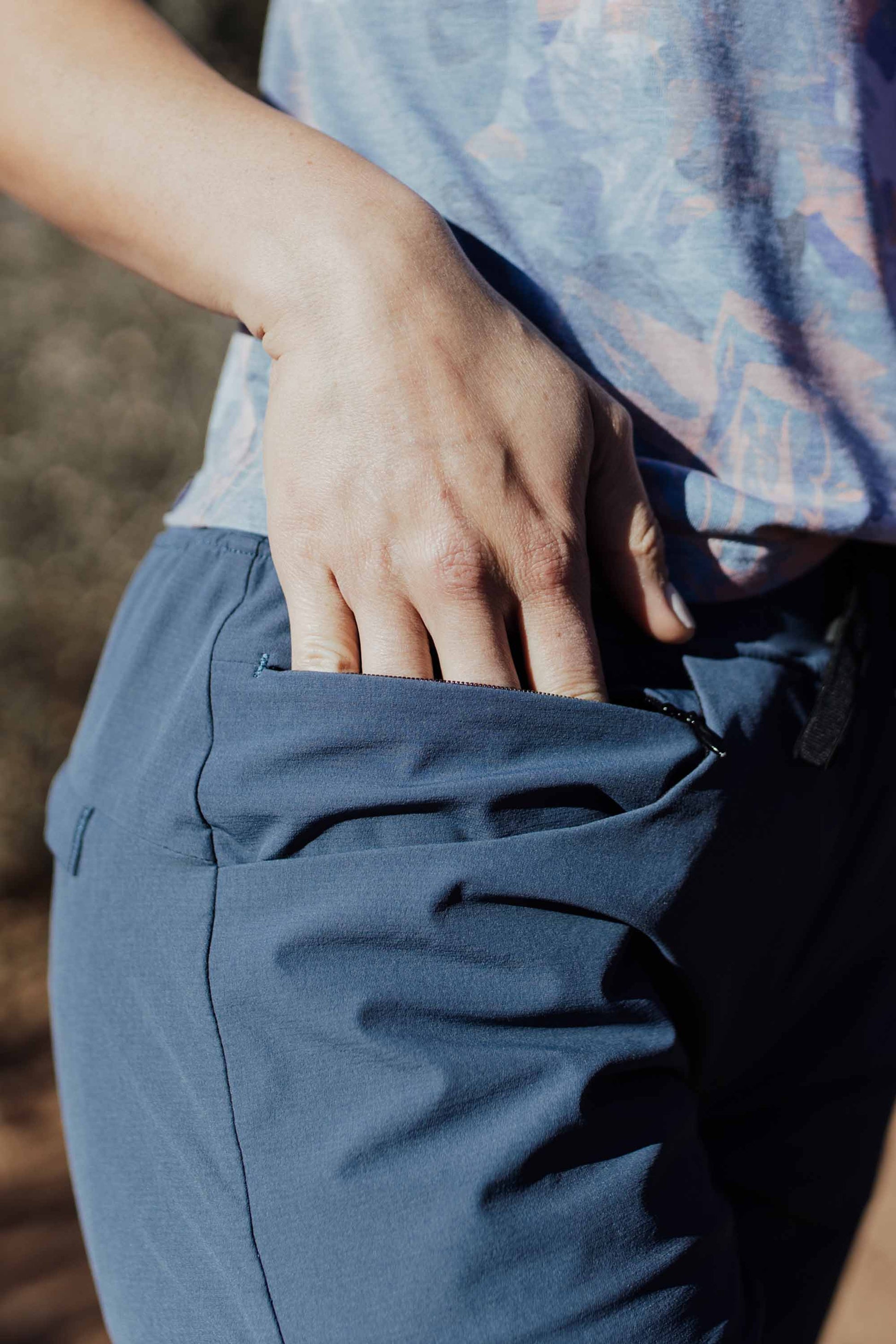 A person wearing Belong Designs' Rocky Mountain Joggers, crafted from durable and stretchy material, stands against a plain background. They are dressed in a dark green cropped top paired with matching athletic pants featuring a drawstring, complemented by brown hiking boots with teal laces. The image is cropped to show the midriff down.
