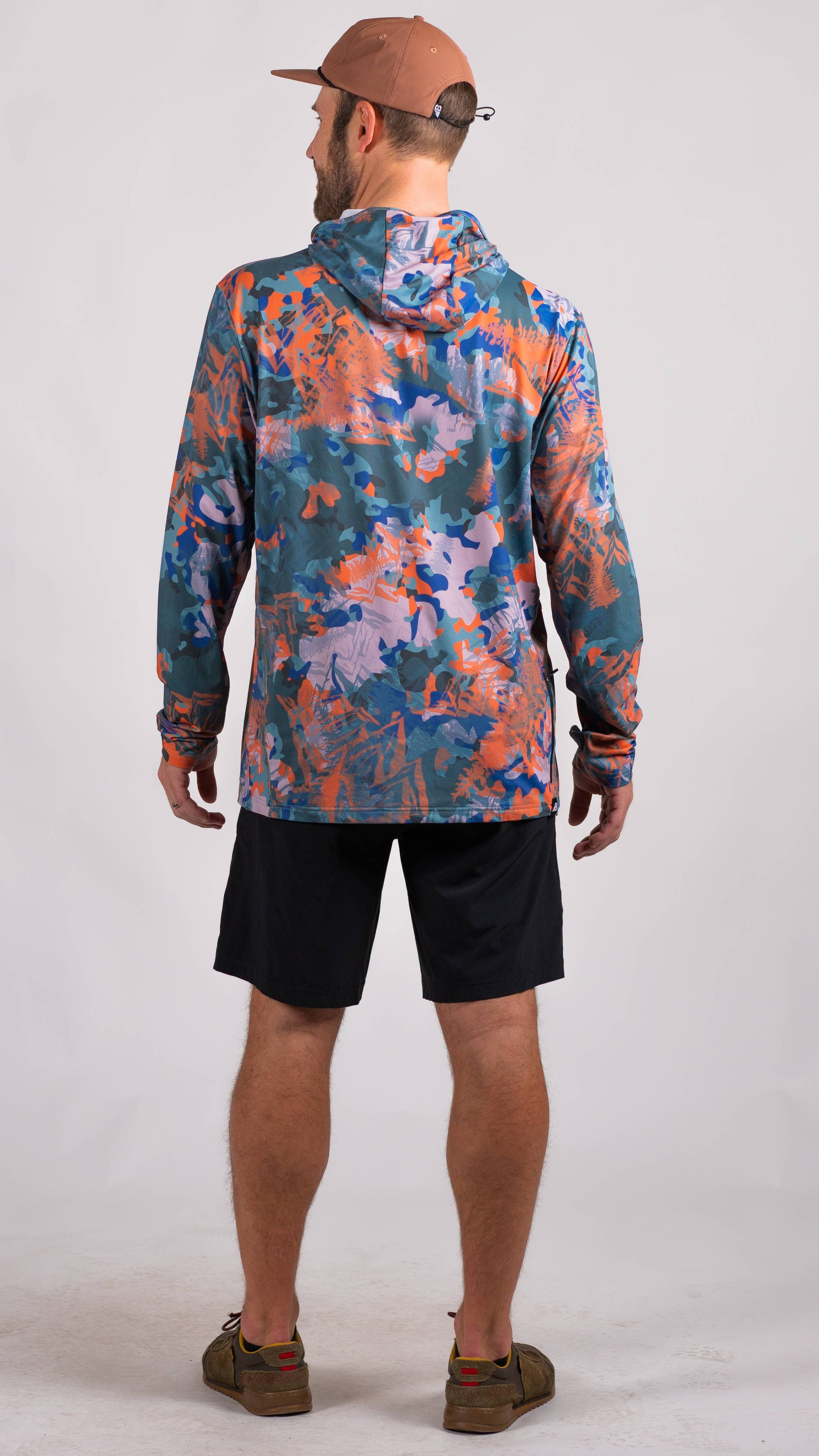 A man is wearing a Belong Designs Men's Sun Hoodie in Green Block, paired with black shorts. The hoodie features a small black logo on the left chest and offers UPF 50+ protection. He is standing against a plain, light-colored background, ready for outdoor activities. His head is not visible in the image.